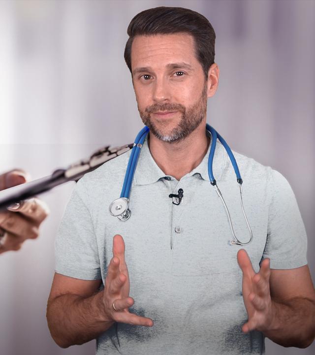 Auf dem Bikd zu sehen ist rechts Host Mirko Drotschmann mit einem Stethoskop um die Schultern. Im Hintergrund zu sehen ist eine Person aus dem Gesundheitsbereich mit Kittel und ebenfalls Stethoskop und einem Klemmbrett in der Hand.