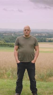 Mann steht breitbeinig auf einem Feld