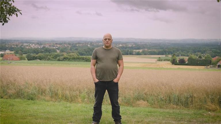 Mann steht breitbeinig auf einem Feld