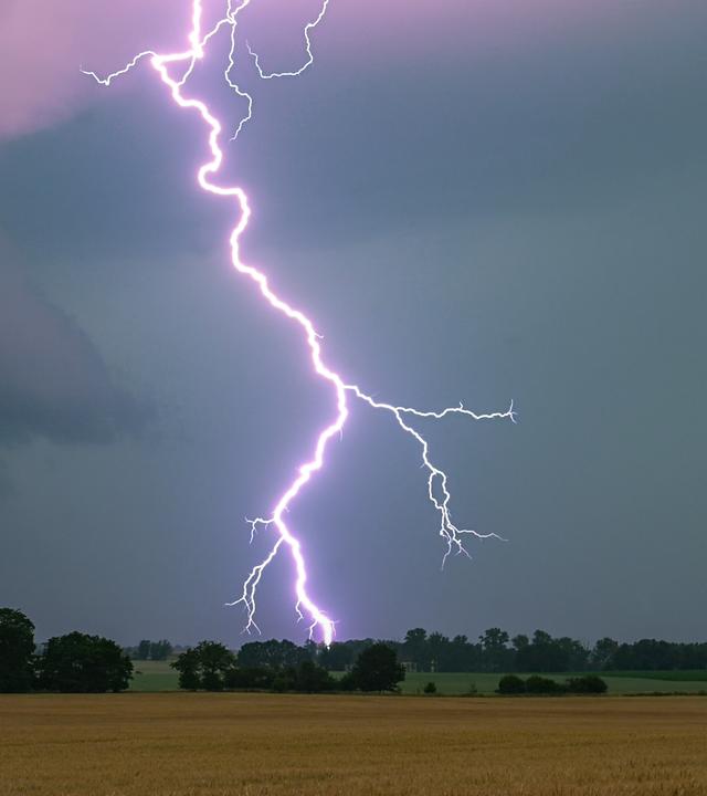 Symbolbild: Ein Blitz leuchtet über einer Landschaft auf. 