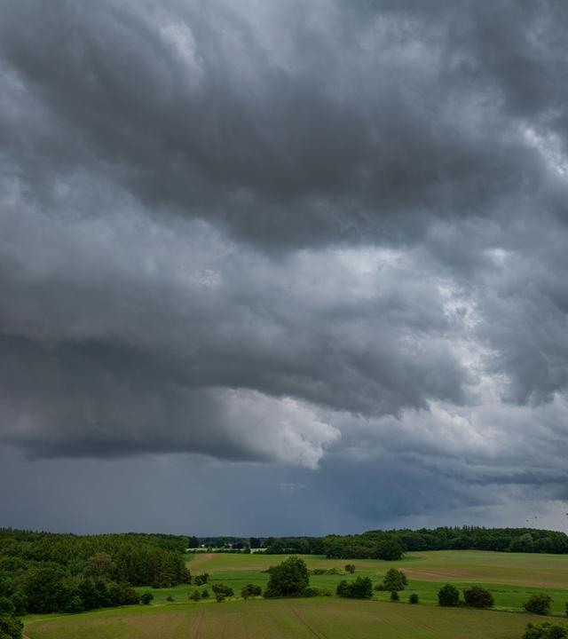 Dunkle Gewitterwolken ziehen über einen Windpark.
