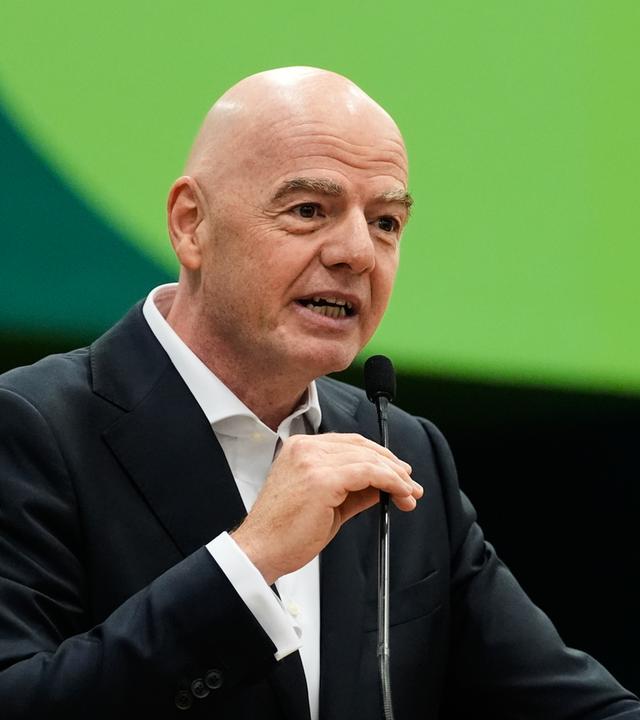 Gianni Infantino spricht in ein Mikrofon vor einem grünen Hintergrund