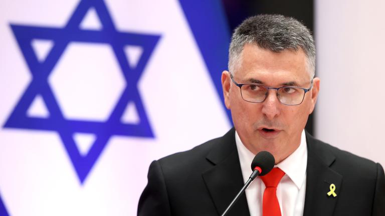 Gideon Saar spricht in ein Mikrofon vor einer israelischen Flagge