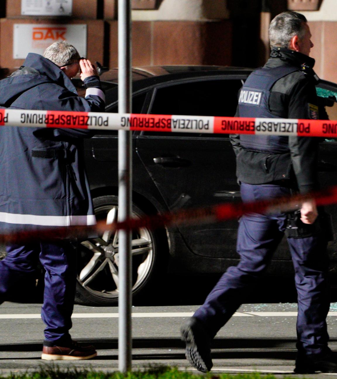 Hessen, Gießen: Zwei Einsatzkräfte der Polizei laufen an dem Unfallfahrzeug, mit einer zerbrochenen Beifahrerscheibe, entlang.
