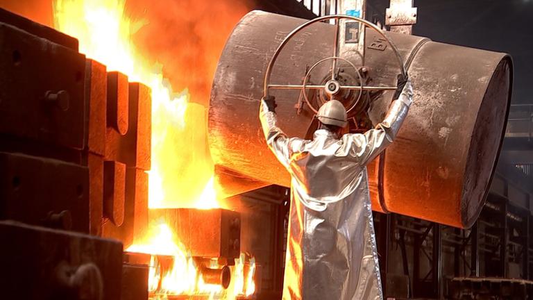 Arbeiter gießt flüssigen Stahl in eine Form