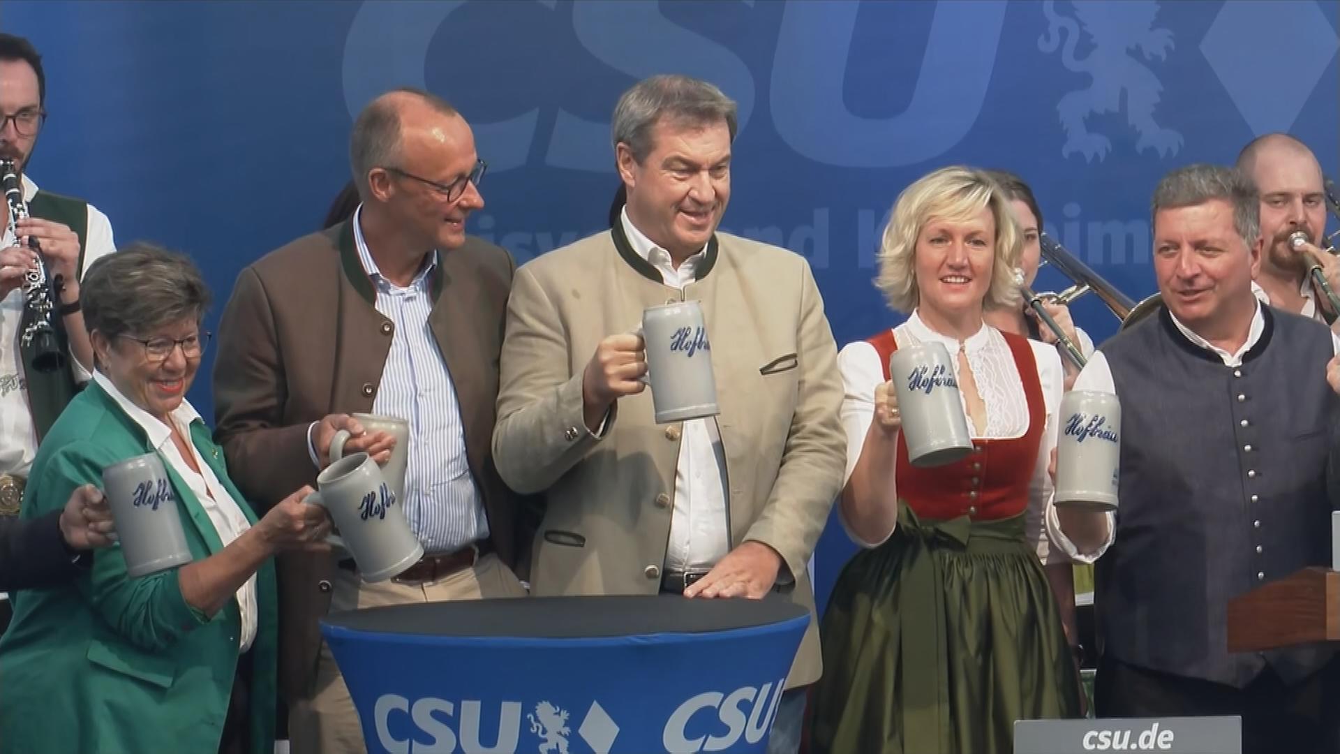 Markus Söder und Friedrich Merz mit Bierseideln auf Bühne bei Gillamoos Volksfest in Abensberg