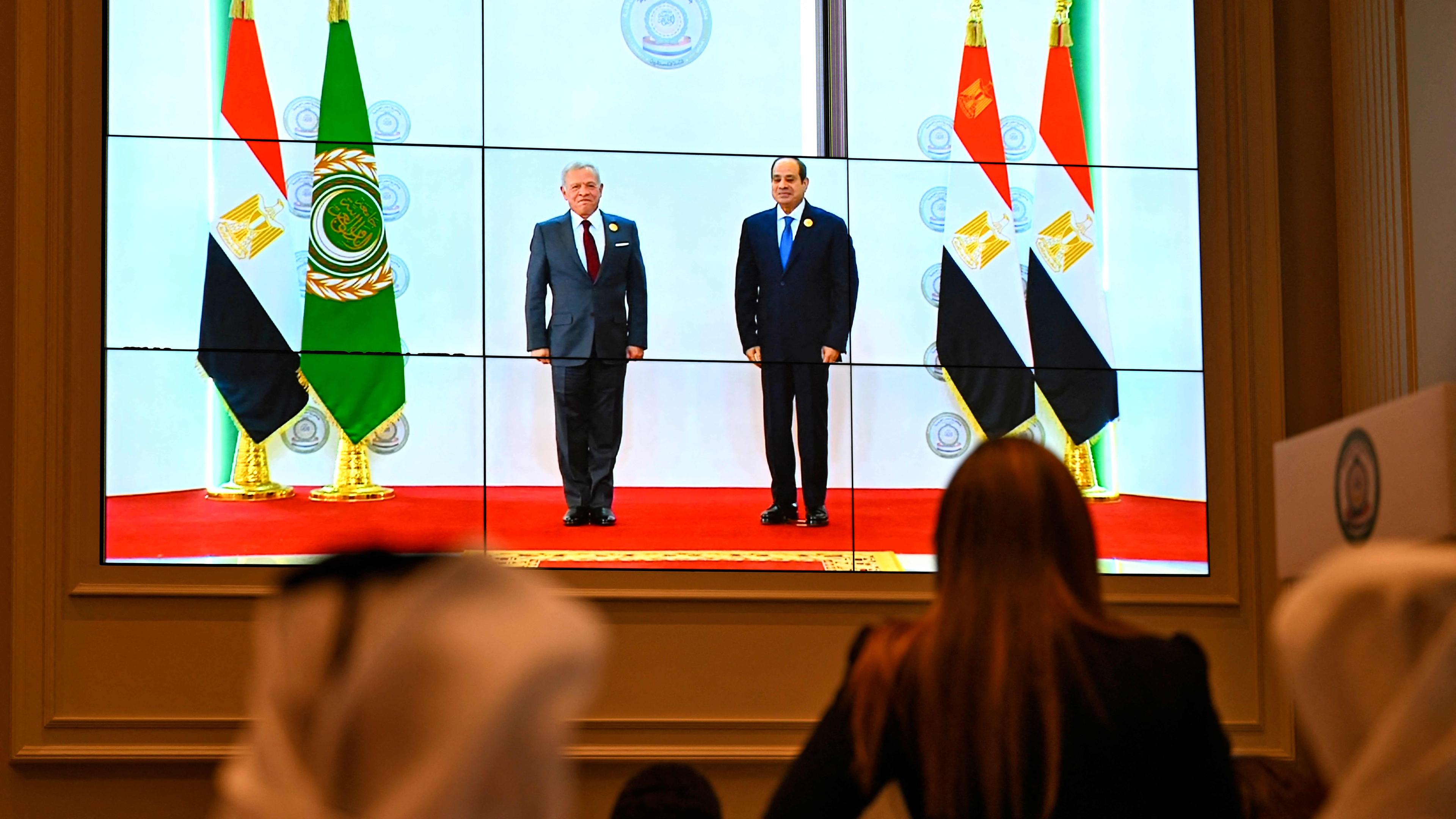 Menschen schauen auf Bildschirm, wo der ägyptische Präsident Abdel Fattah al-Sisi Jordaniens König King Abdullah II begrüßt. 