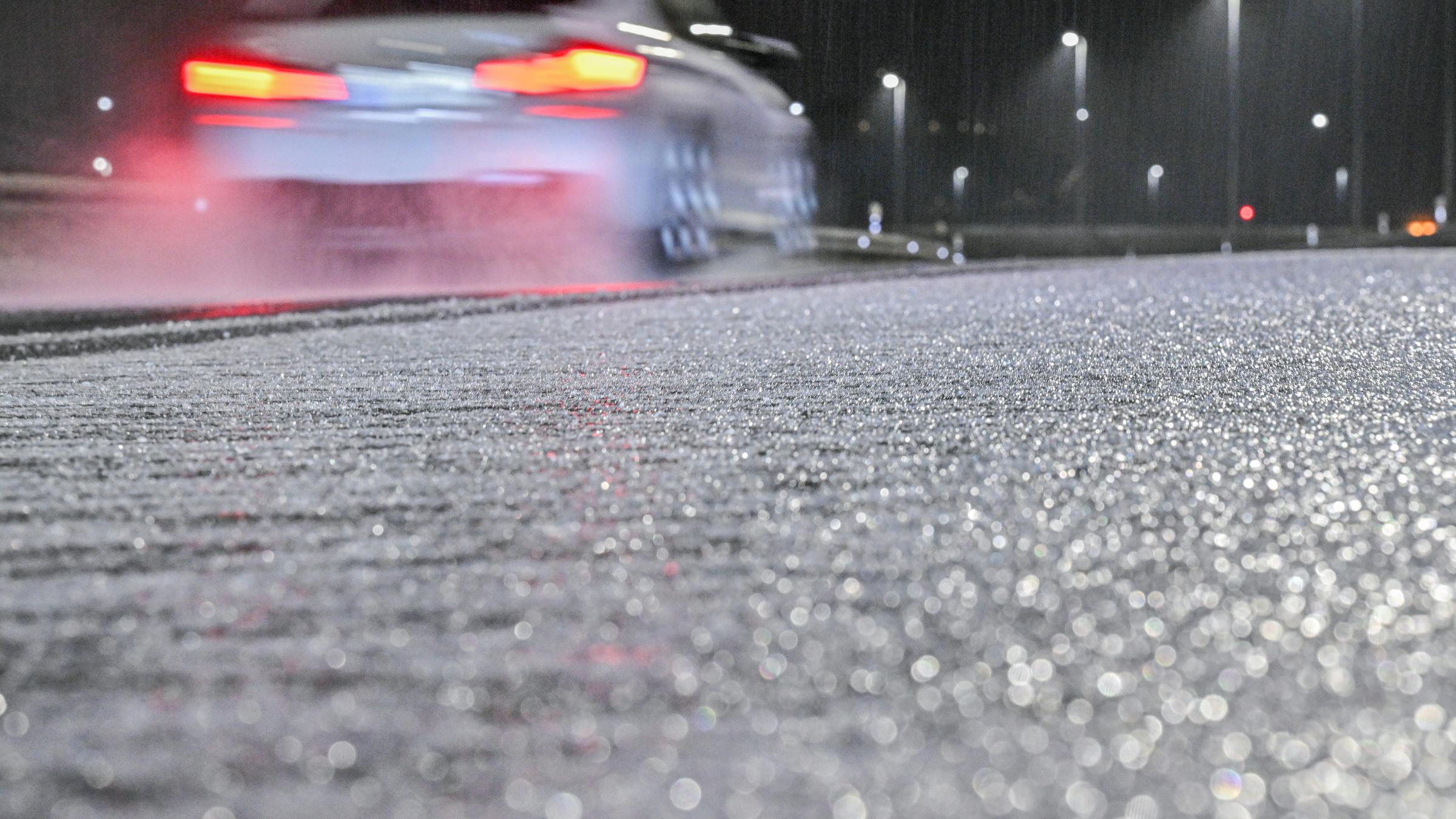 24.11.2025, Bayern, München: Ein Auto fährt in der Nähe des Flughafens München an Eis auf einer Straße vorbei. 