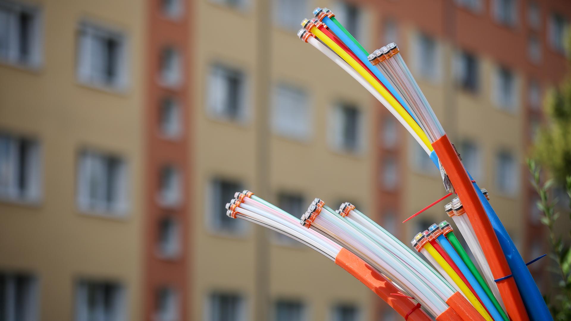 Aus dem Sockel eines Schaltschranks ragen Glasfaserkabel heraus.