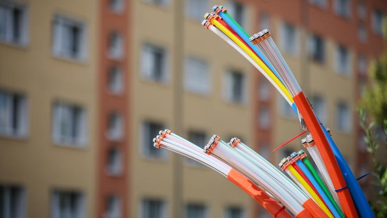 Aus dem Sockel eines Schaltschranks ragen Glasfaserkabel heraus.