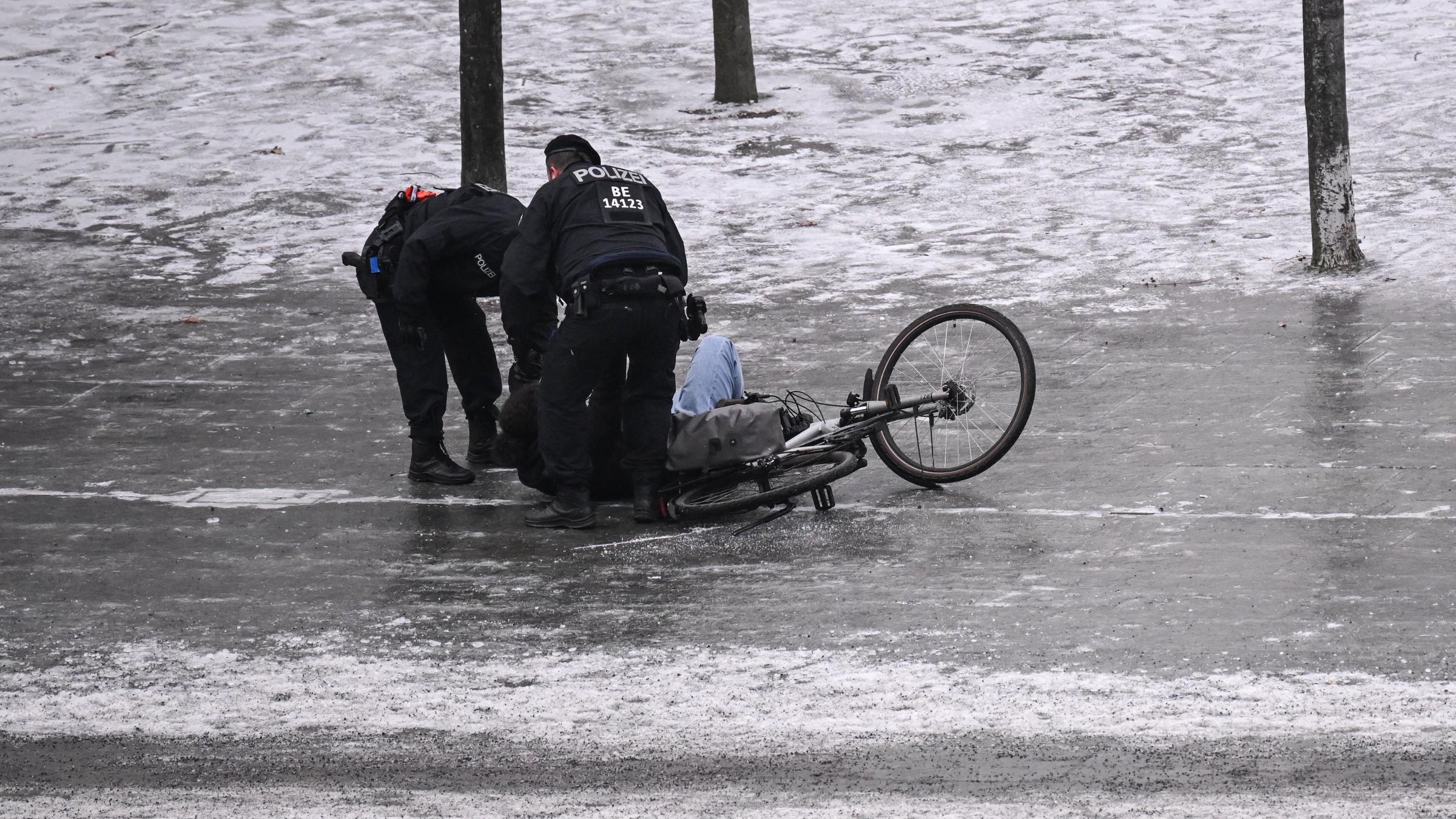 Berlin: Polizisten helfen einem Fahrradfahrer, der bei Glatteis ausgerutscht ist