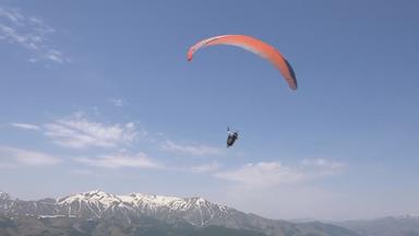Ein Paraglider mit einem Schirm in orange. 