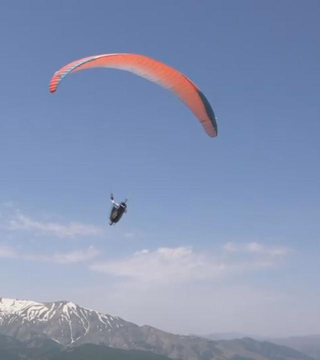 Ein Paraglider mit einem Schirm in orange. 