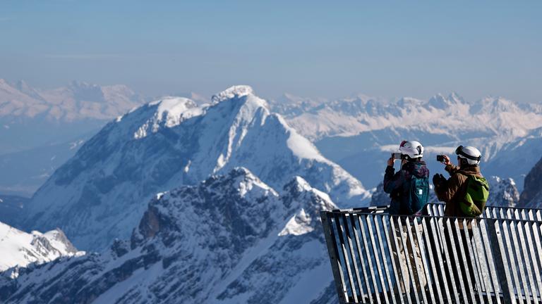 Von einem Aussichtspunkt im Skigebiet Zugspitze bei Garmisch-Partenkirchen blicken die Menschen auf die Stelle, wo der Schneefernerkopf-Lift abgebaut wird.