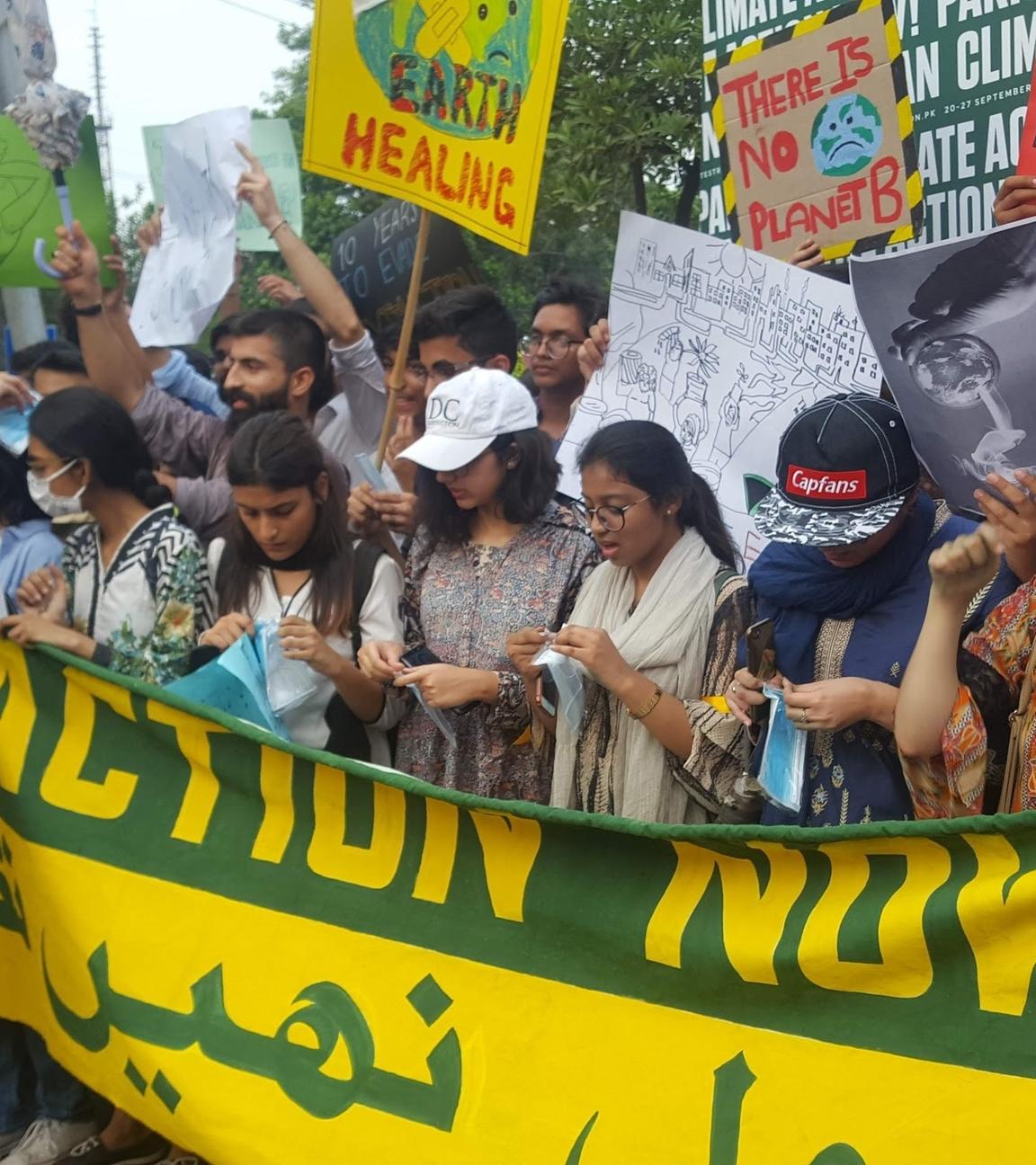 Junge Menschen, vor allem Mädchen, halten ein Banner und mehrere Schilder, die ein Handeln gegen den Klimawandel fordern. Einige tragen eine Gesichtsmaske.