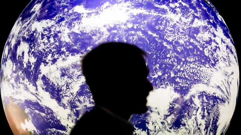 Schatten eines Kopfes vor einem leuchtenden Globus (Symbolbild)