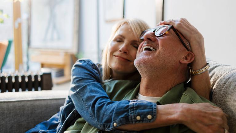 Lächelndes, ältere Pärchen auf dem Sofa.