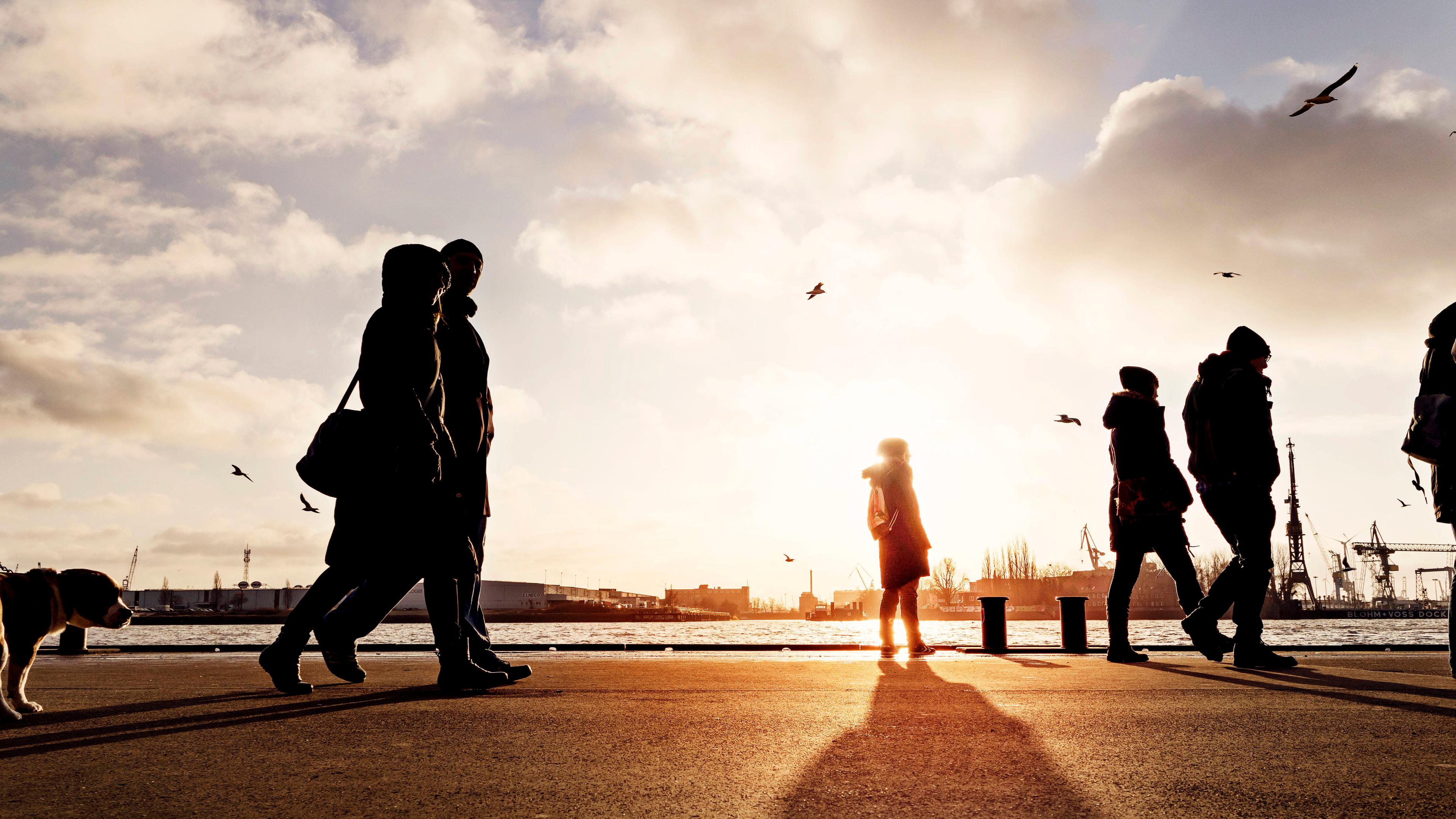 Eine Frau steht an einer Hamburger Anlegestelle und Passanten gehen vorbei.