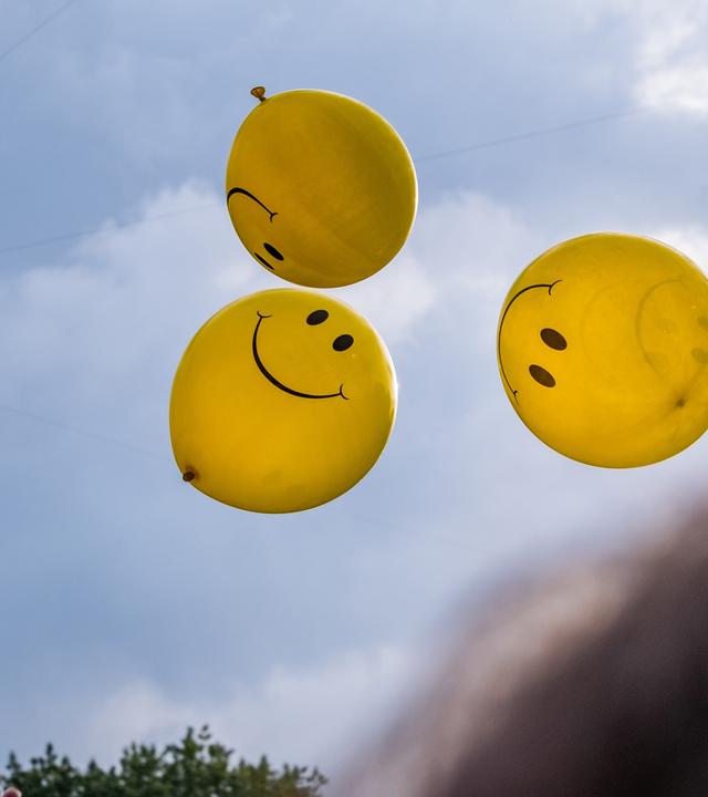 Smiley-Ballons fliegen in die Luft. 
