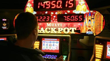 Mann spielt an einem Glücksspielautomaten in einer Spielhalle