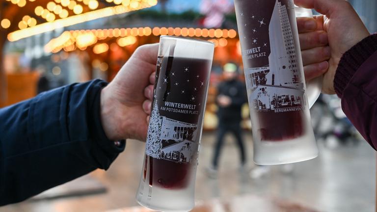 Berlin: Mit zwei Gläsern Glühwein stoßen Besucher vom Weihnachtsmarkt "Winterwelt Potsdamer Platz Berlin" an.