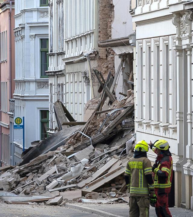 Einsatzkräfte von Polizei und Feuerweht stehen in der Nähe eines eingestürzten Hauses in der Innenstadt von Görlitz