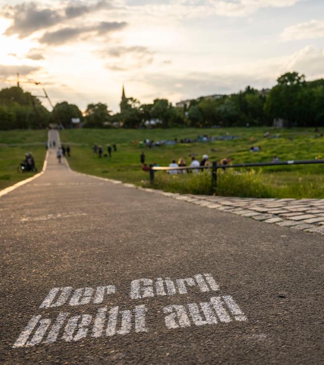 Besucher sitzen bei Sonnenuntergang im Görlitzer Park. 