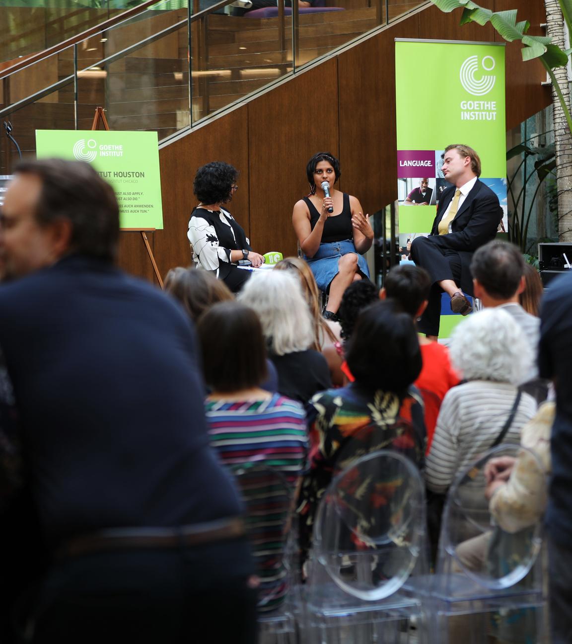 Bei einer Veranstaltung sitzen mehrere Personen auf einem Podium vor Zuschauern und reden.