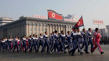 Eine Gruppe nordkoreanischer Regierungsbeamter joggt in Pjoengjang über den Kim-Il-Sung-Platz.