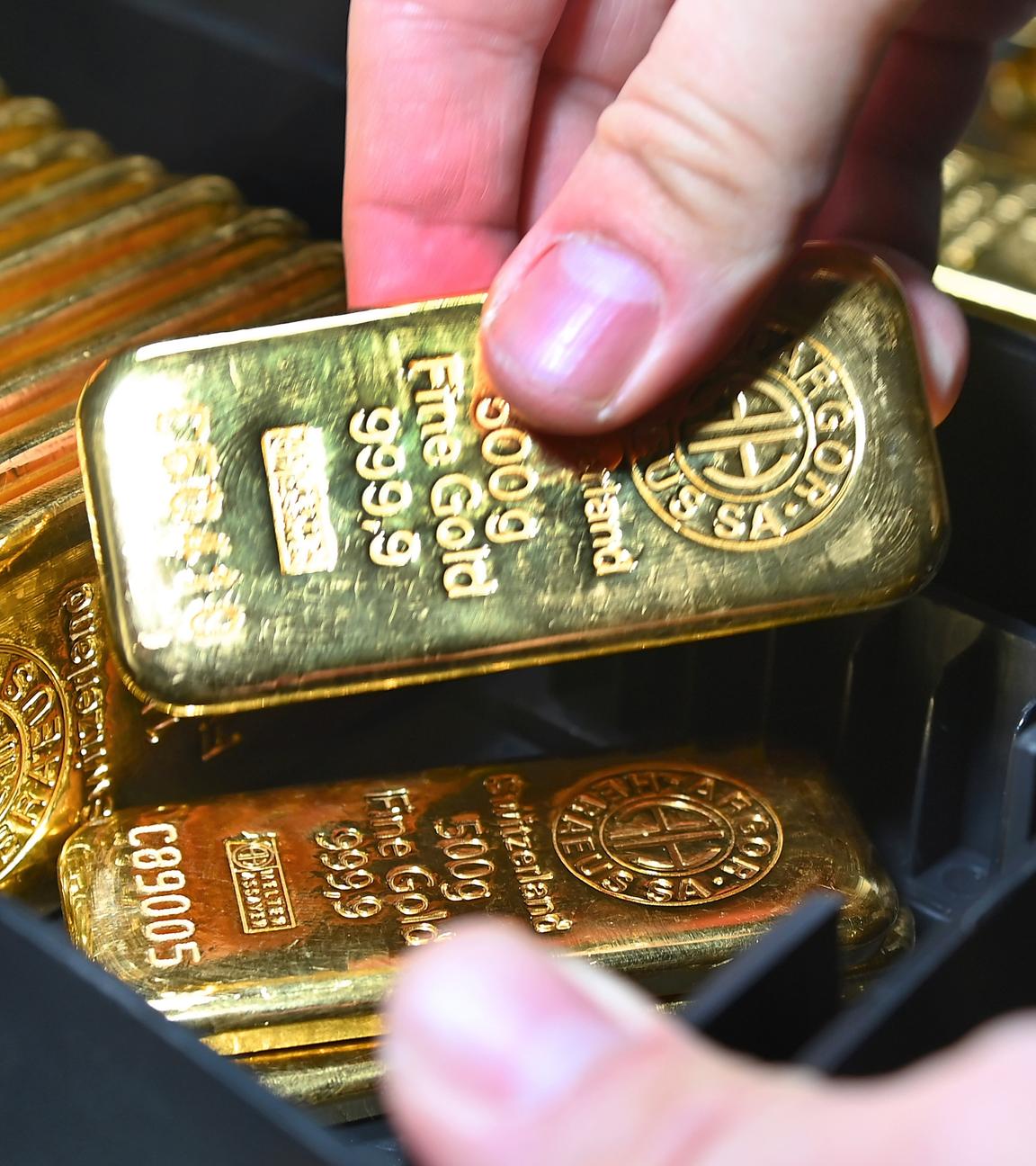 Eine Person zählt Goldbarren in einem Tresorraum.