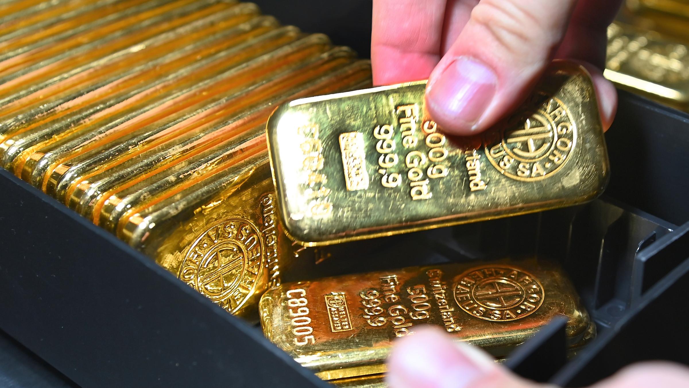Eine Person zählt Goldbarren in einem Tresorraum.