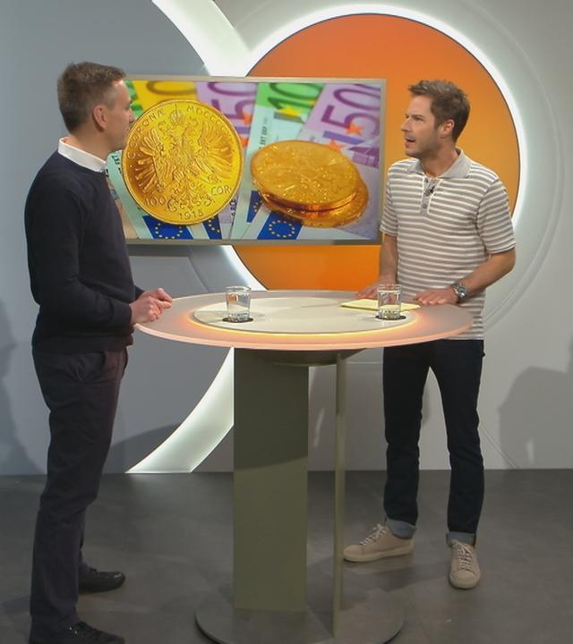 Christian Urban mit Florian Weiss im Volle-Kanne-Studio. Im Hintergrund ein Bildschirm mit Goldmünzen.