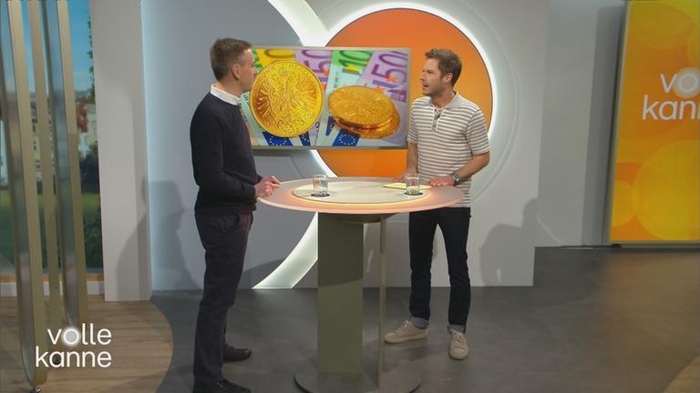 Christian Urban mit Florian Weiss im Volle-Kanne-Studio. Im Hintergrund ein Bildschirm mit Goldmünzen.