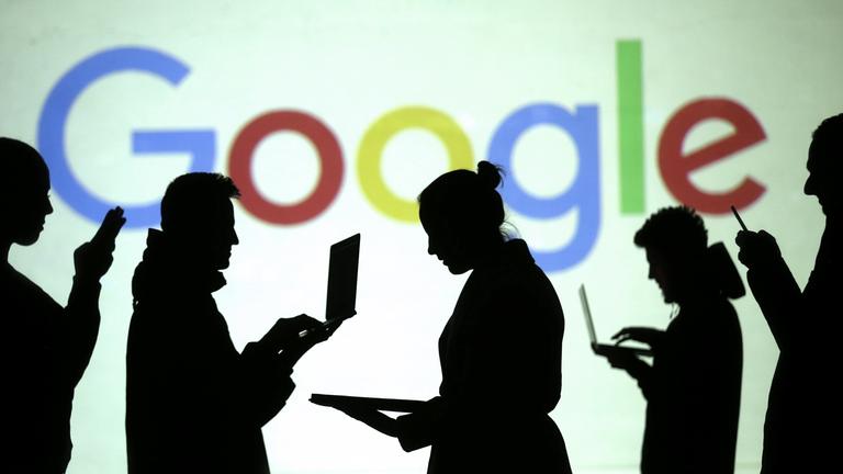 Schatten von Laptop-Nutzern vor Google Logo