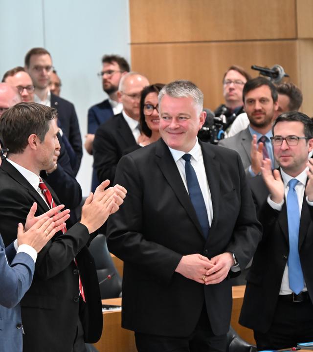 Der neue rheinland-pfälzische Ministerpräsident Gordon Schnieder nach seiner Wahl im rheinland-pfälzischen Landtag in Mainz. Die Personen um ihn herum applaudieren.