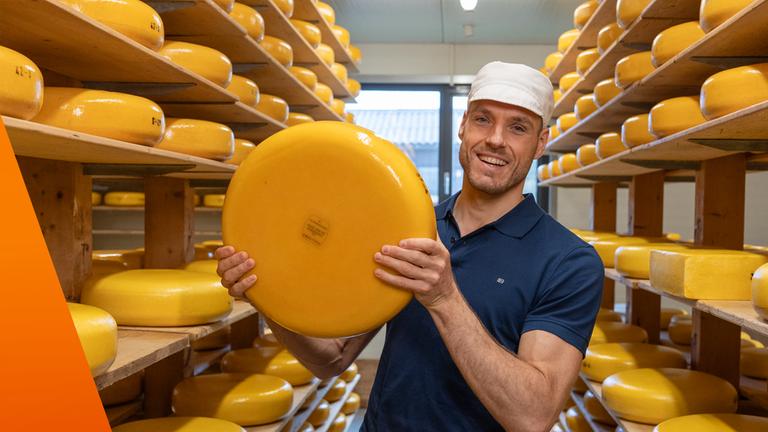 Mann hält großen Gouda-Käselaib in der Hand 