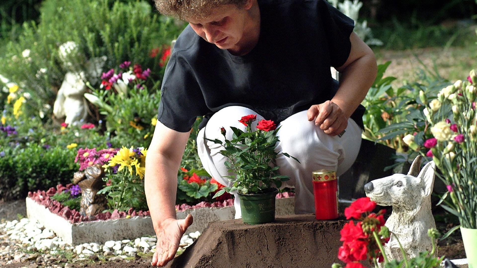 Frau pflegt Grab auf Tierfriedhof