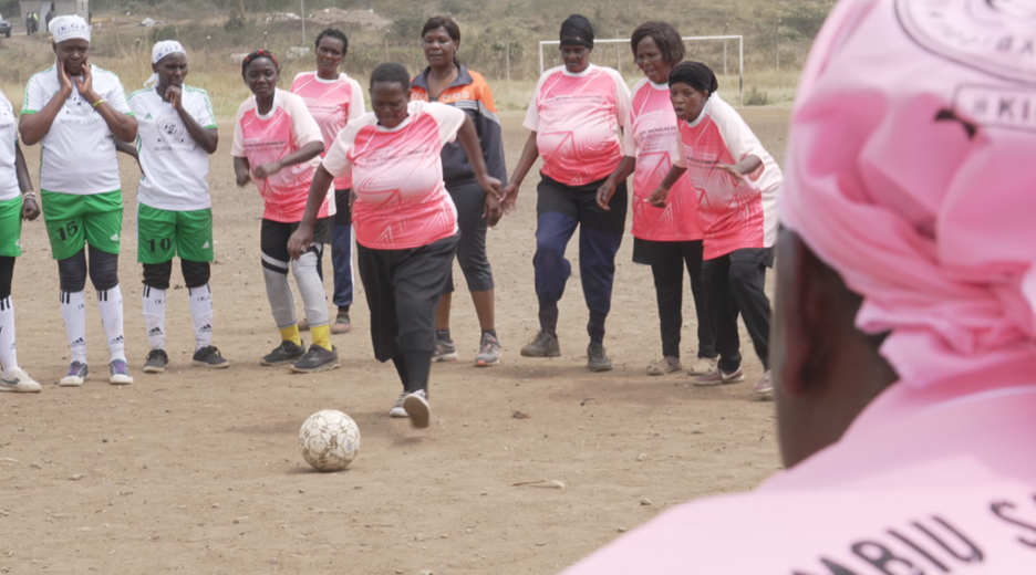 Kenias Fußball-Omas: Mit vollem Einsatz für Gesundheit und Gemeinschaft. Frauen stehen auf einem Feld und eine kickt den Ball.