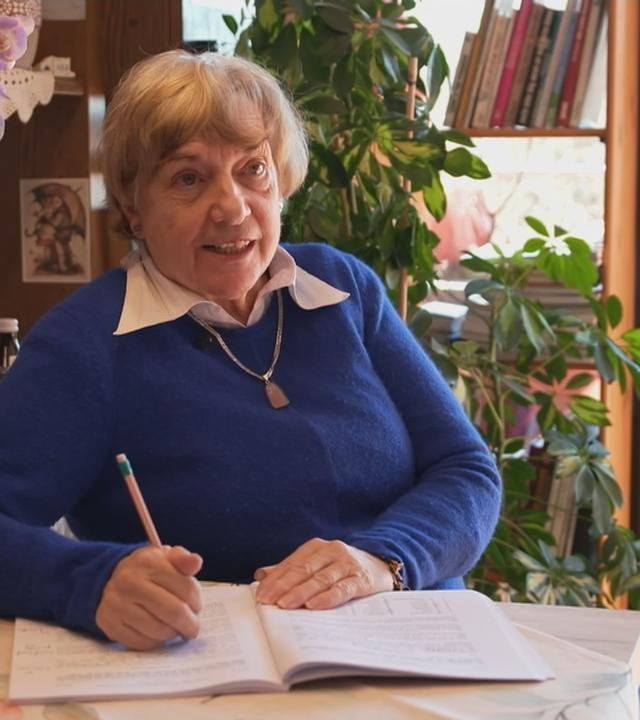 Andrea Kemmler sitzt am Schreibtisch und schreibt in ein Heft.