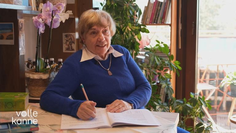 Andrea Kemmler sitzt am Schreibtisch und schreibt in ein Heft.