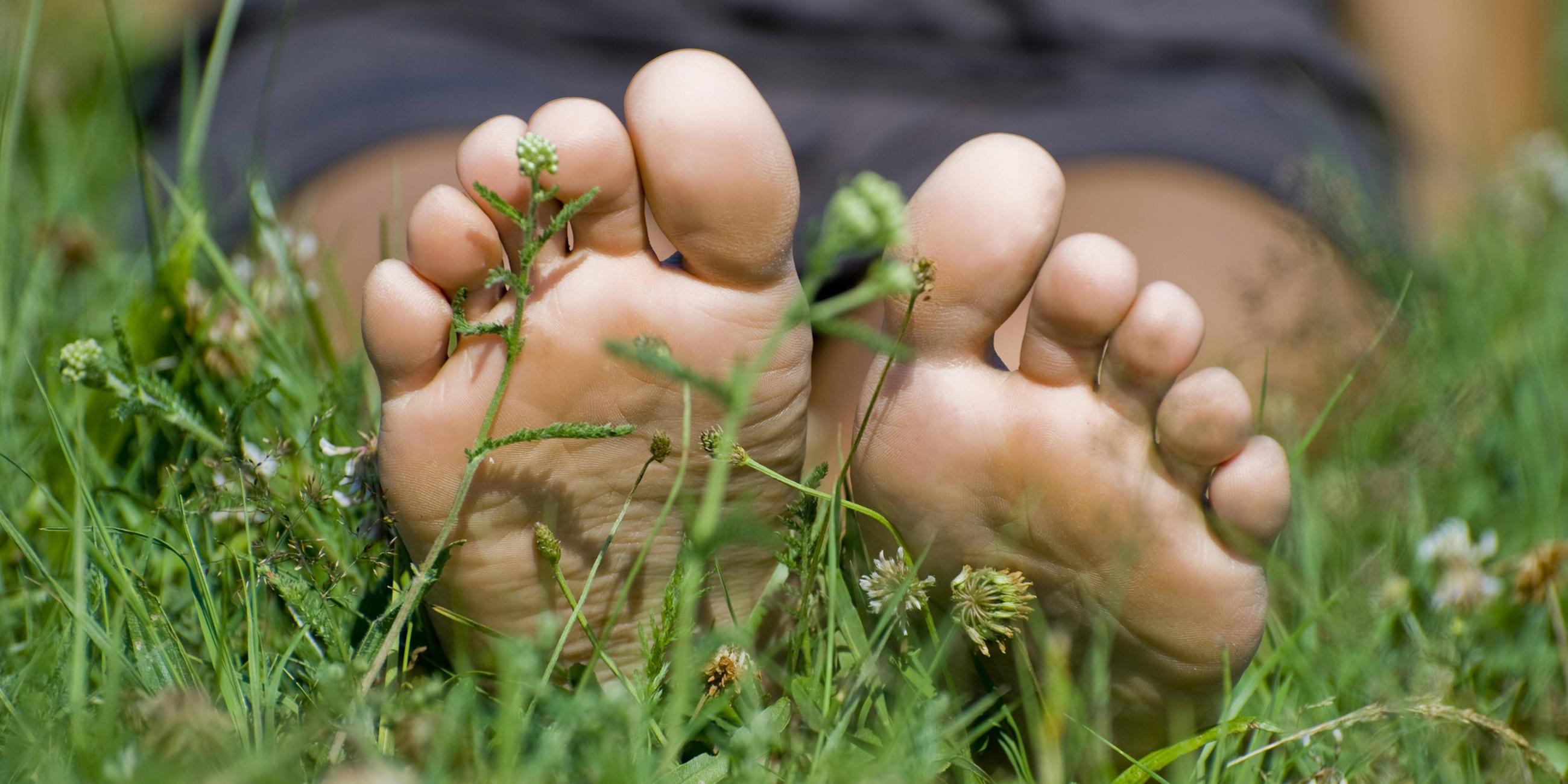 Frau sitzt barfuss auf der Wiese