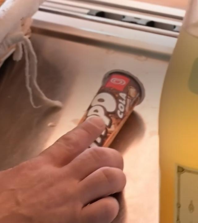 Eine Hand schiebt ein Wassereis über einen Verkaufstresen.