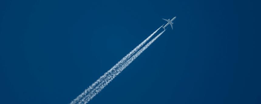 Ein Verkehrsflugzeug zieht am Himmel Kondensstreifen hinter sich her.