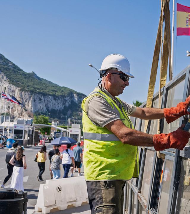 Vor der Kulisse des Felsens von Gibraltar bauen Arbeiter am Montag, dem 0607.2026, in La Línea de la Concepción (Spanien) einen spanischen Grenzkontrollpunkt ab