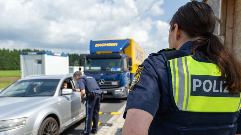03.06.2025, Wildenau: Ein Polizist überprüft die Dokumente eines Fahrzeugführers im Rahmen einer Grenzkontrolle
