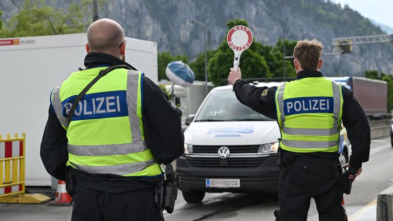 Zwei Beamte der Bundespolizei kontrollieren ein Fahrzeug an einem Grenzübergang entlang der Deutsch-Österreichischen Grenze.