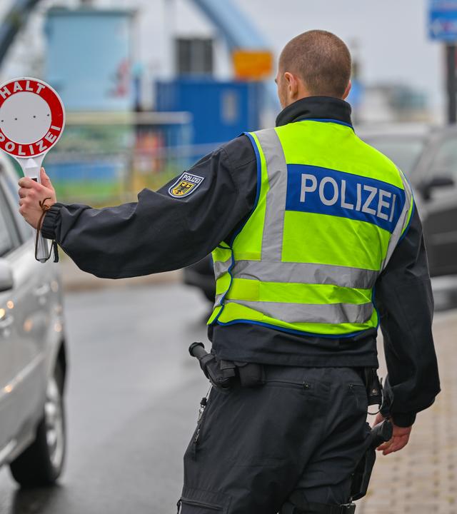 Ein Polizist stoppt an der deutsch-polnischen Grenze einen Wagen.