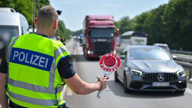Ein Beamter der Bundespolizei steht auf der Autobahn A12 nahe dem deutsch-polnischen Grenzübergang und stoppt ein Auto mit polnischen Fußballfans, die unterwegs nach Berlin zum EM-Spiel Polen gegen Österreich sind.