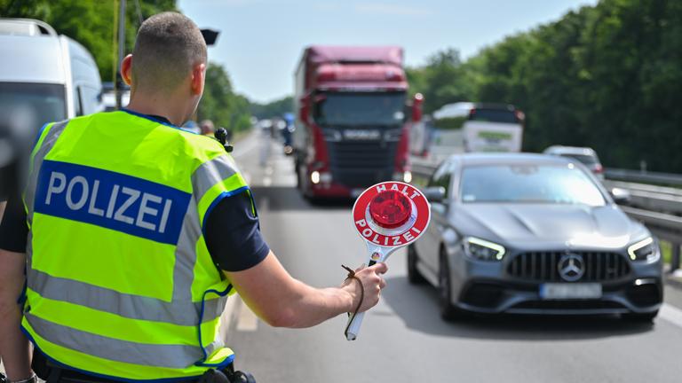 Ein Beamter der Bundespolizei steht auf der Autobahn A12 nahe dem deutsch-polnischen Grenzübergang und stoppt ein Auto mit polnischen Fußballfans, die unterwegs nach Berlin zum EM-Spiel Polen gegen Österreich sind.