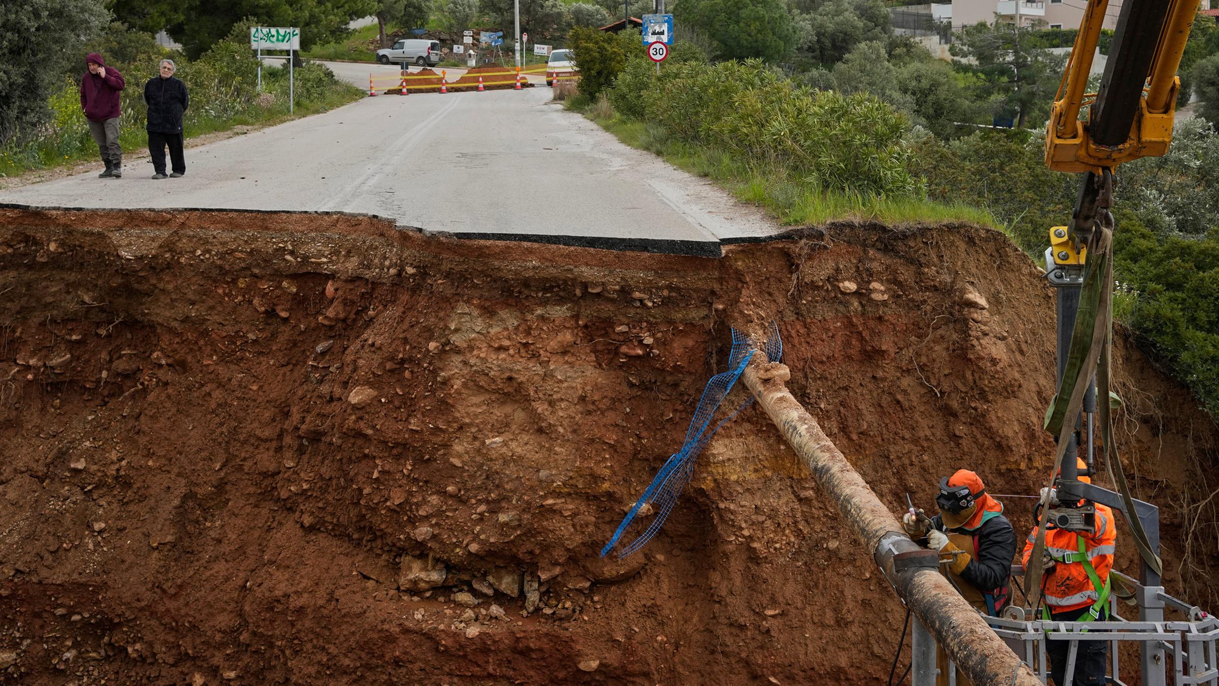 Arbeiter reparieren am 2. April 2026 in Kallitechnoupoli, einem Vorort von Athen, eine beschädigte Wasserleitung an einer aufgerissenen Straße, nachdem schwere nächtliche Unwetter große Schäden verursacht haben.